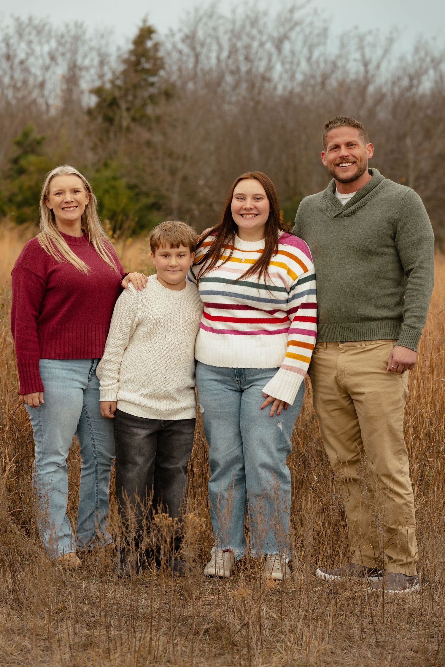 Family members pose together in a field wearing coordinated casual outfits.