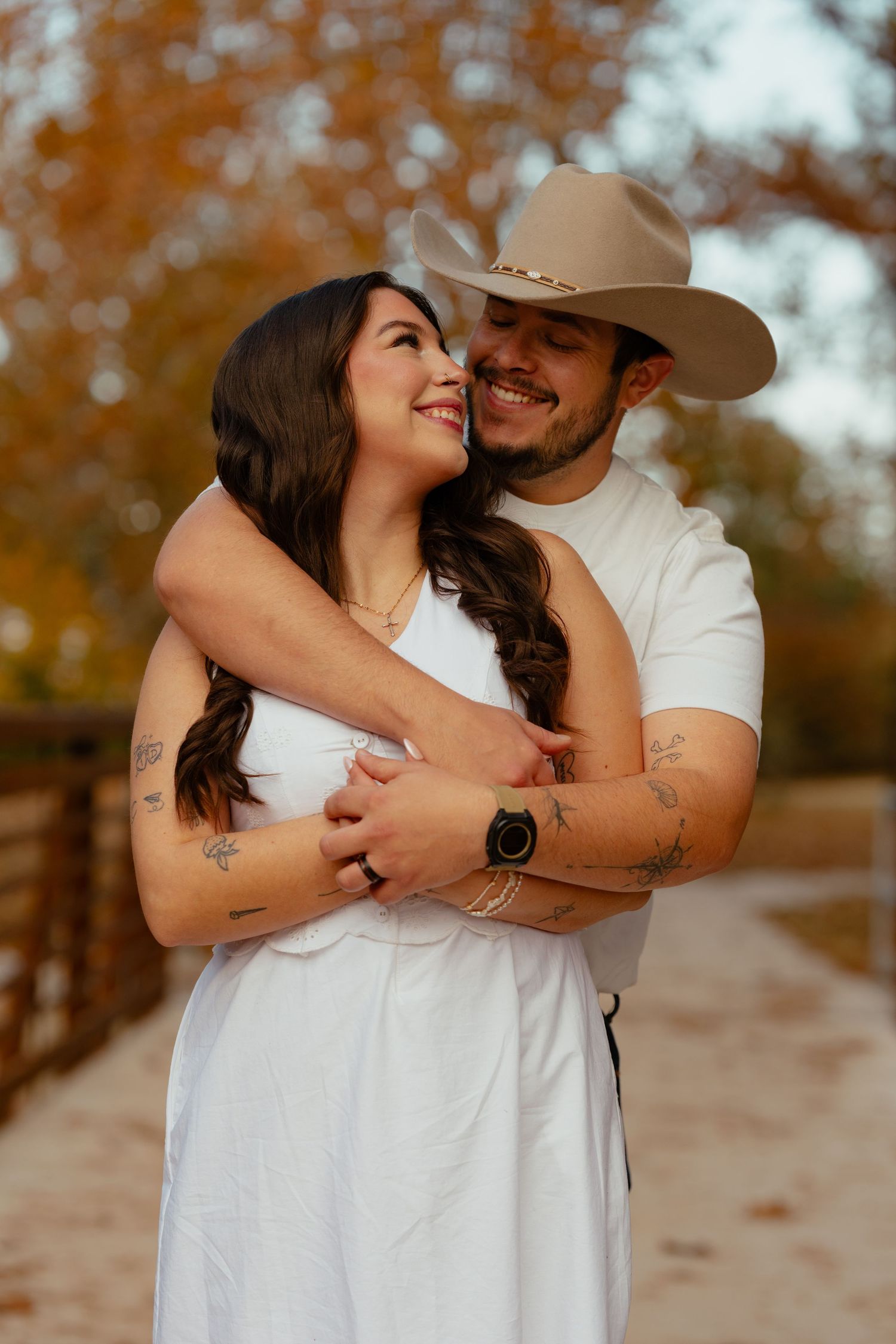 Intimate couple portrait showing affectionate embrace against fall foliage background.