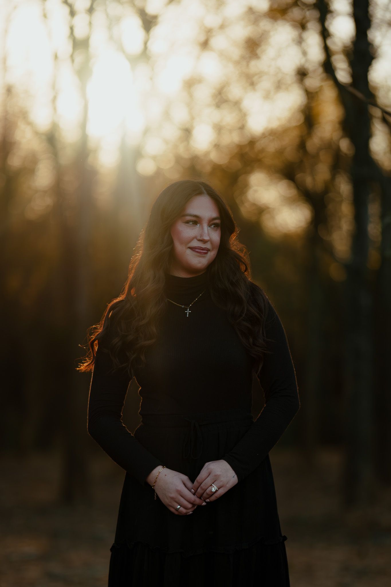 Golden hour portrait in wooded setting with backlit subject wearing dark clothing.