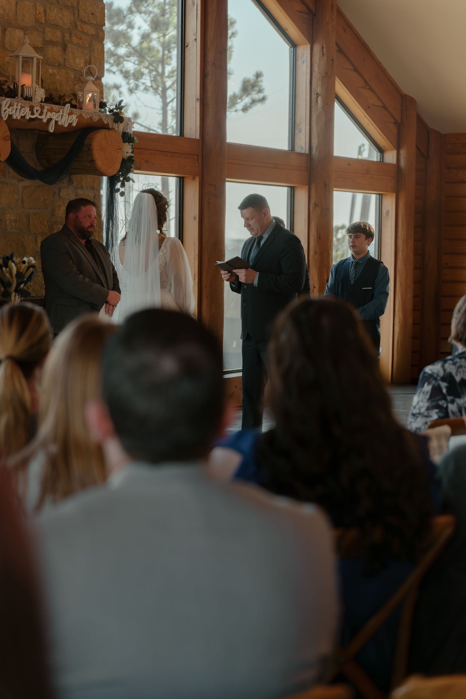 Wedding ceremony taking place in a rustic wooden lodge with large windows and natural light streaming in.