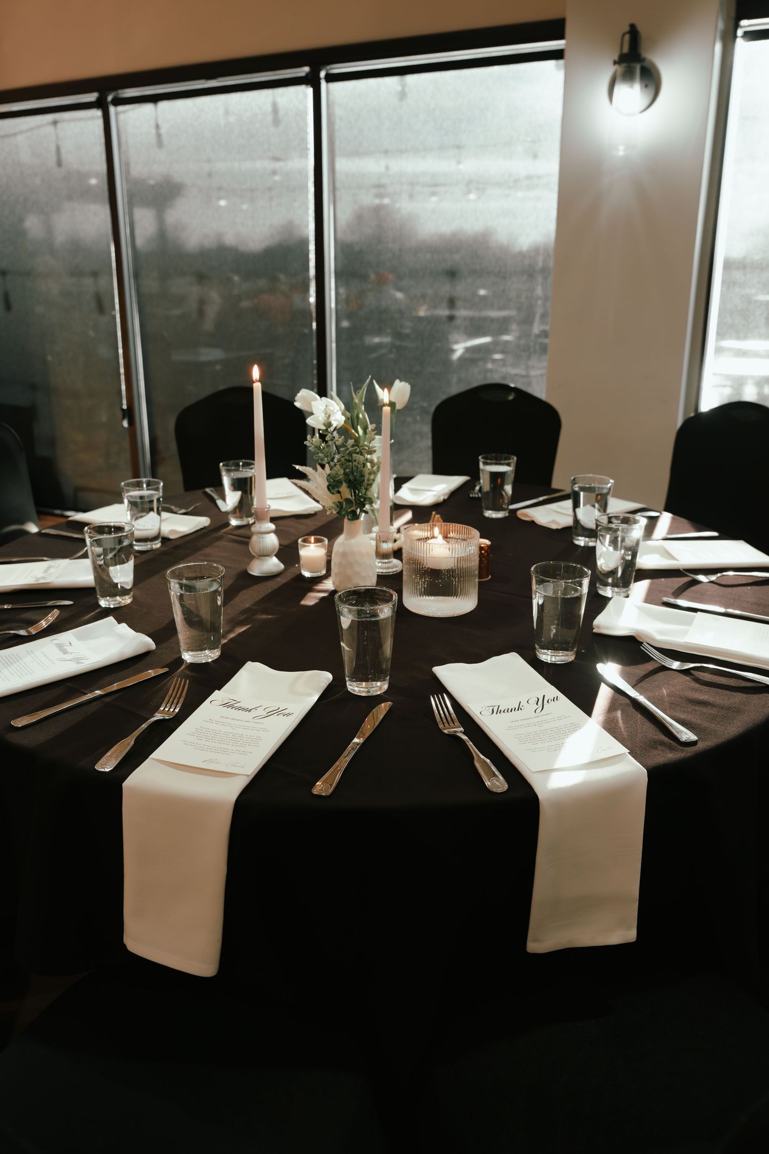 Elegant round banquet table with black linen, white napkins, candles, and floral centerpiece set for a formal event.