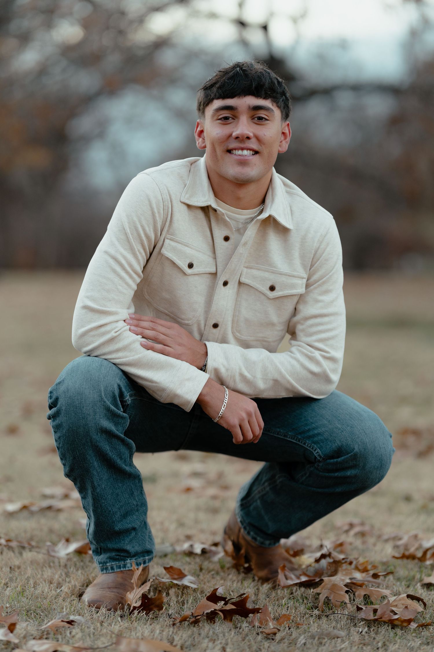 Autumn outdoor portrait with fallen leaves featuring casual denim and cream jacket styling.