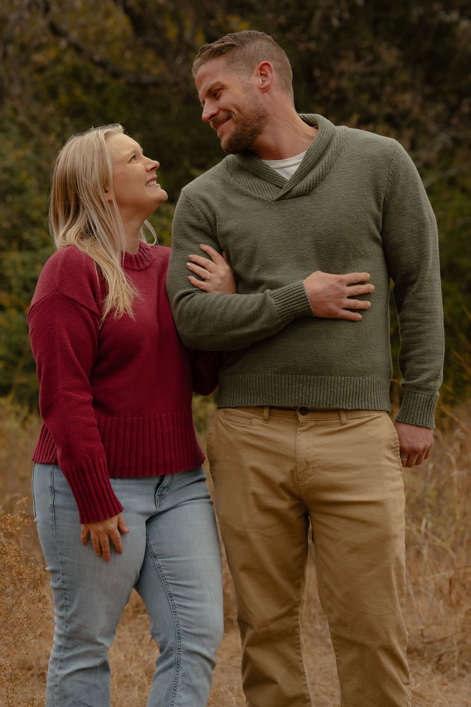 Couple sharing intimate laughs during an outdoor photo session in cozy sweaters.