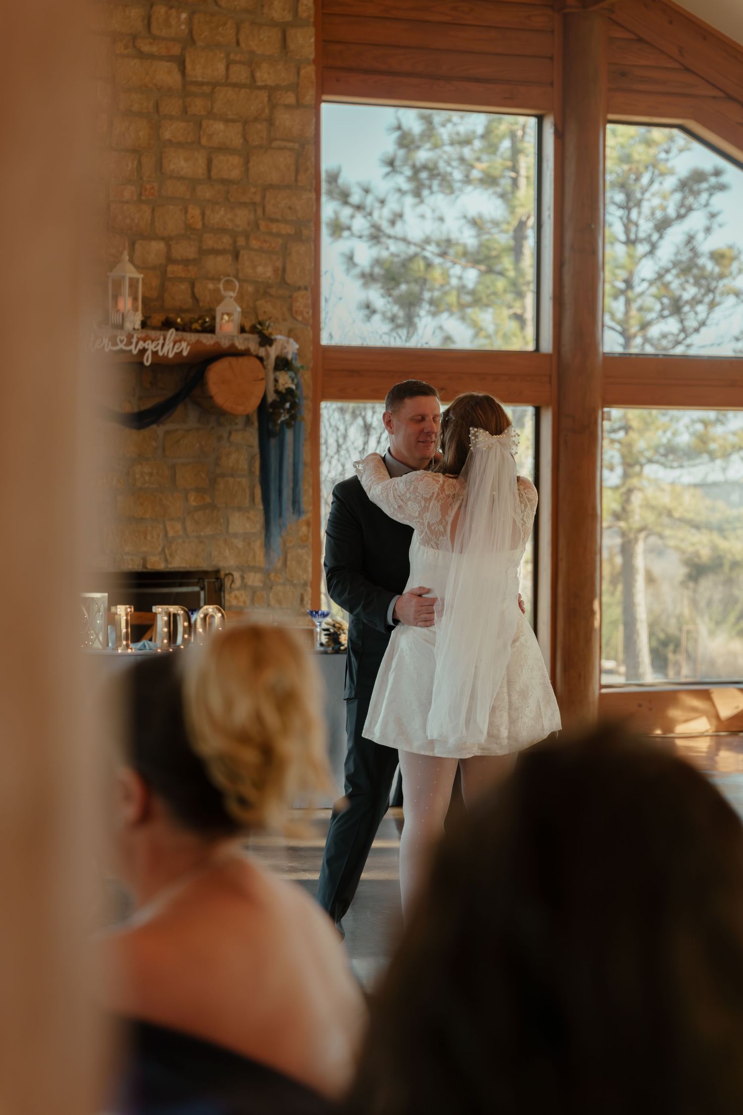 A wedding ceremony unfolds in a rustic stone and wood venue with natural light streaming through tall windows.