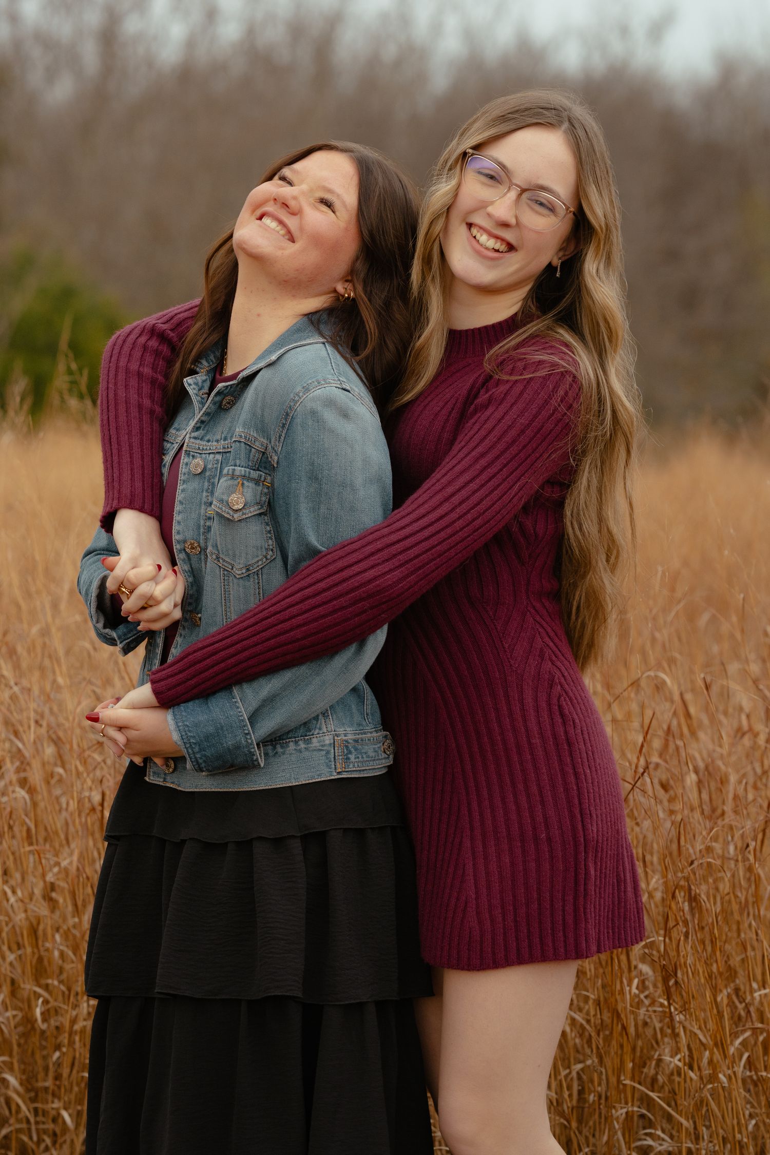 Two friends sharing joyful laughter together in a field of tall grass.