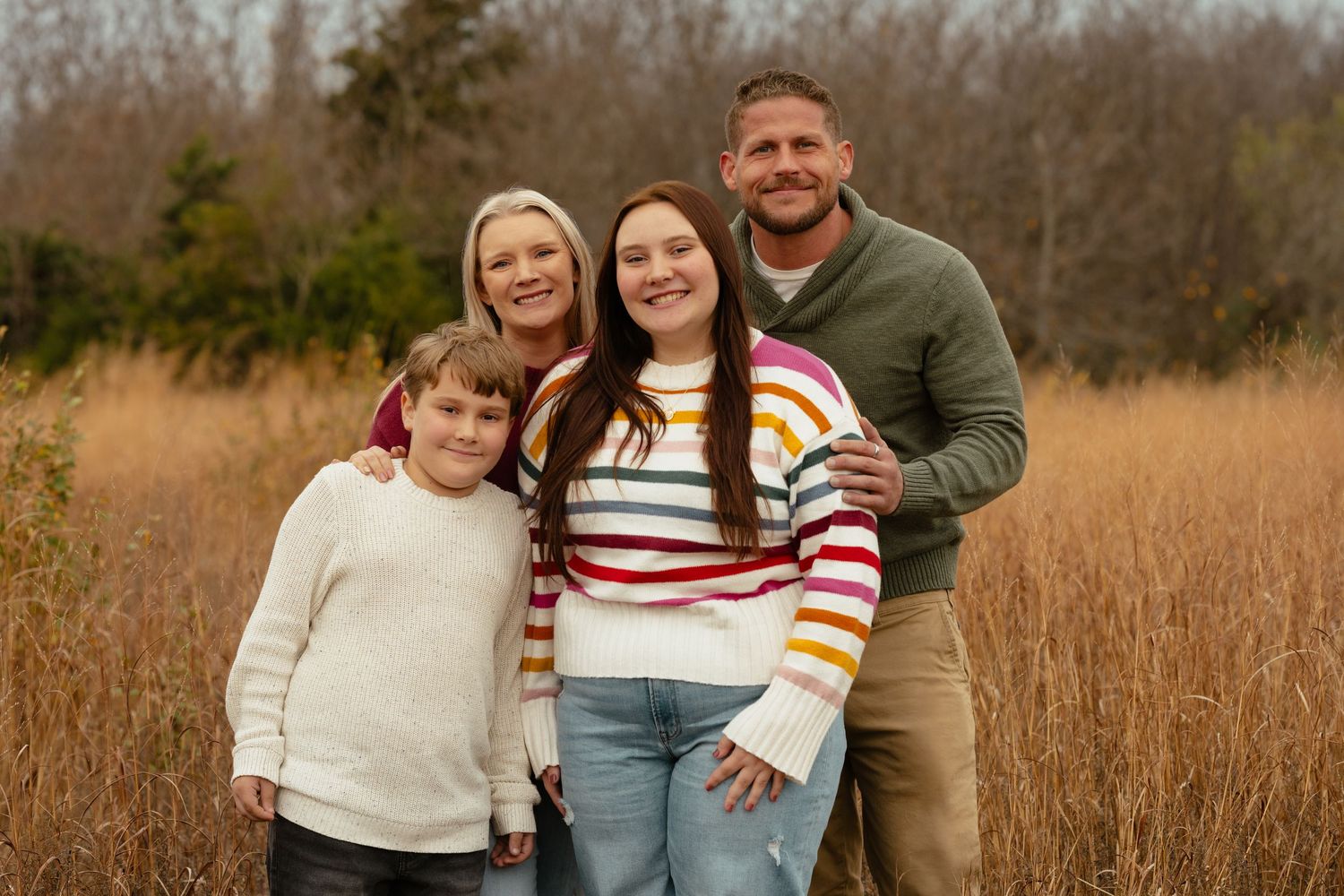 A joyful family photo session captured in a rustic field setting.