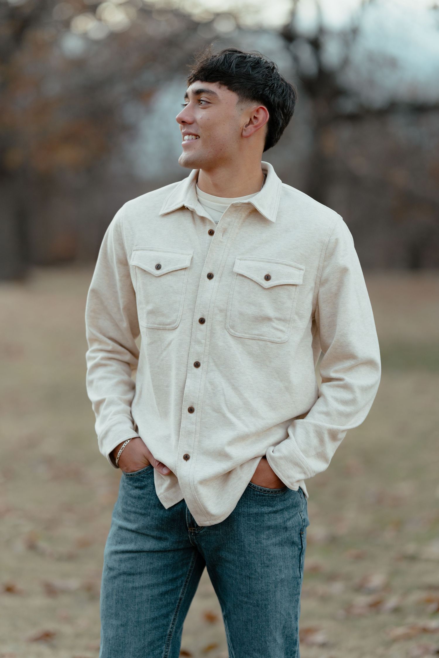 Casual outdoor portrait showing someone in cream button-down shirt against autumn background.