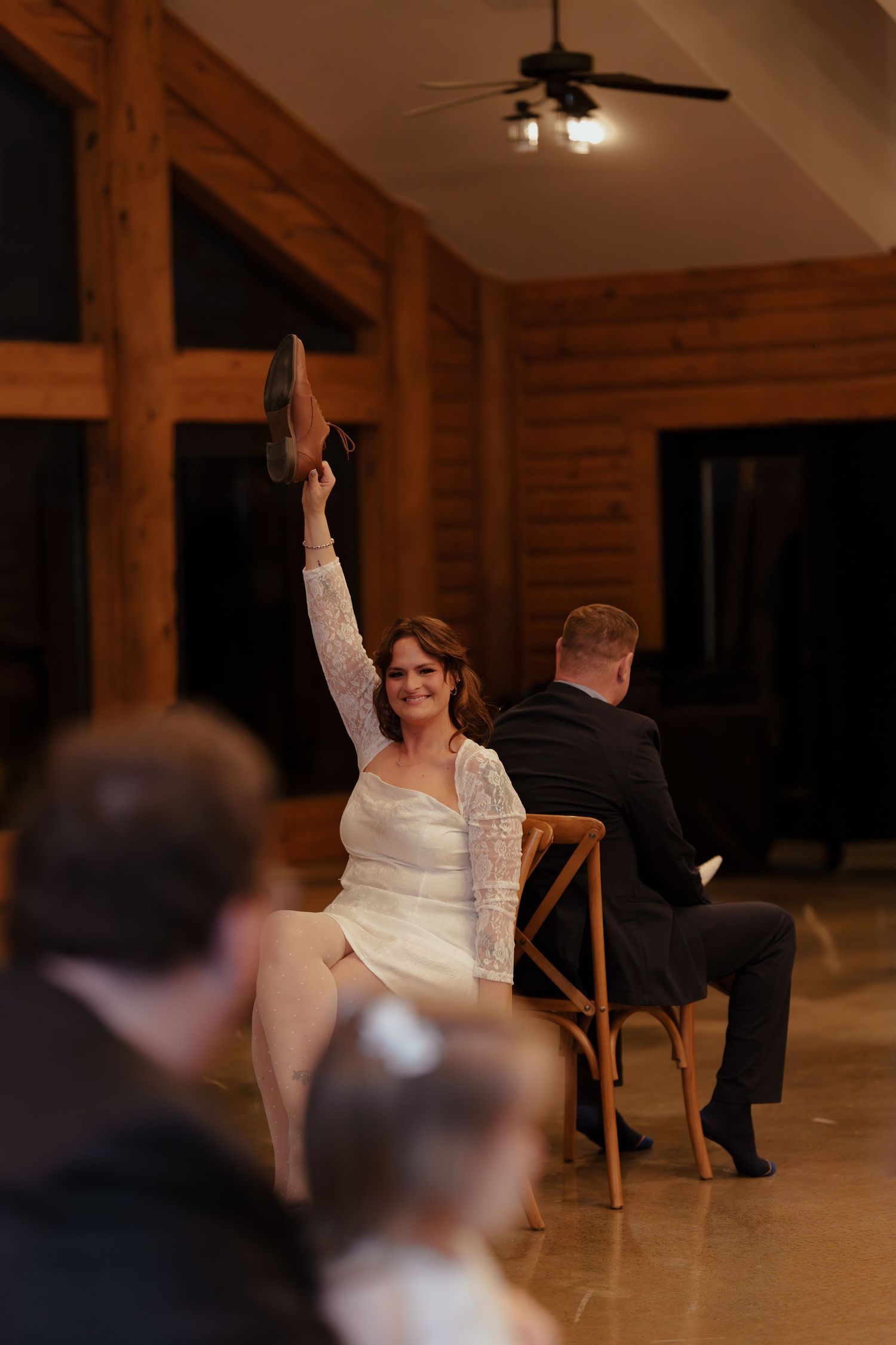 Wedding guests participate in a fun reception game with chairs in a rustic wooden lodge venue.