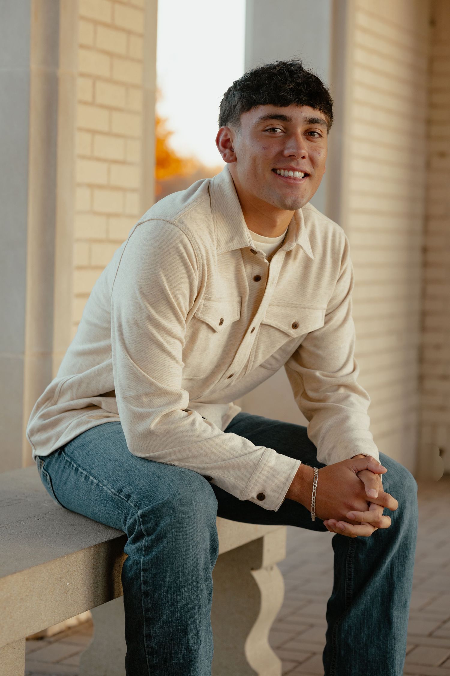 A relaxed portrait of someone in casual attire sitting on brick steps.