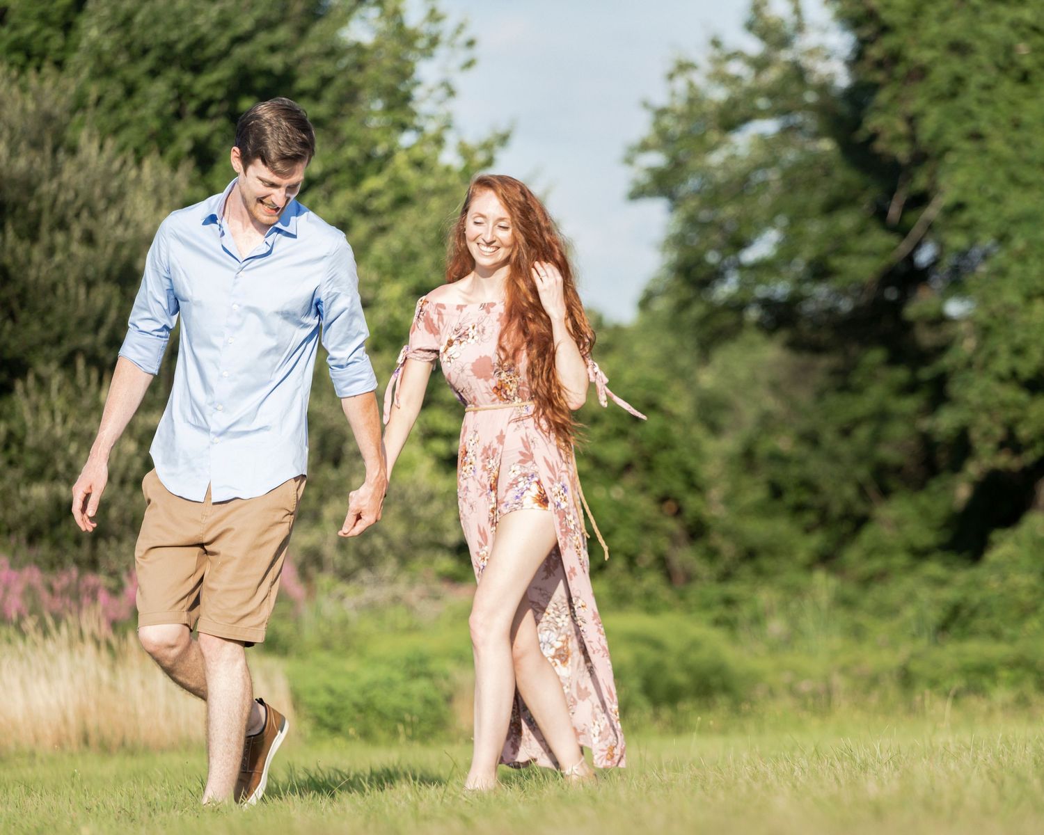 Couple running playfully through a green meadow on a sunny summer day.