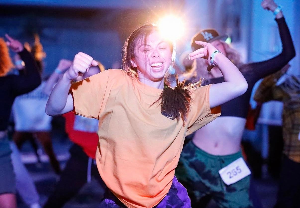 People dancing and having fun at a nightclub with colorful lighting and energetic atmosphere.