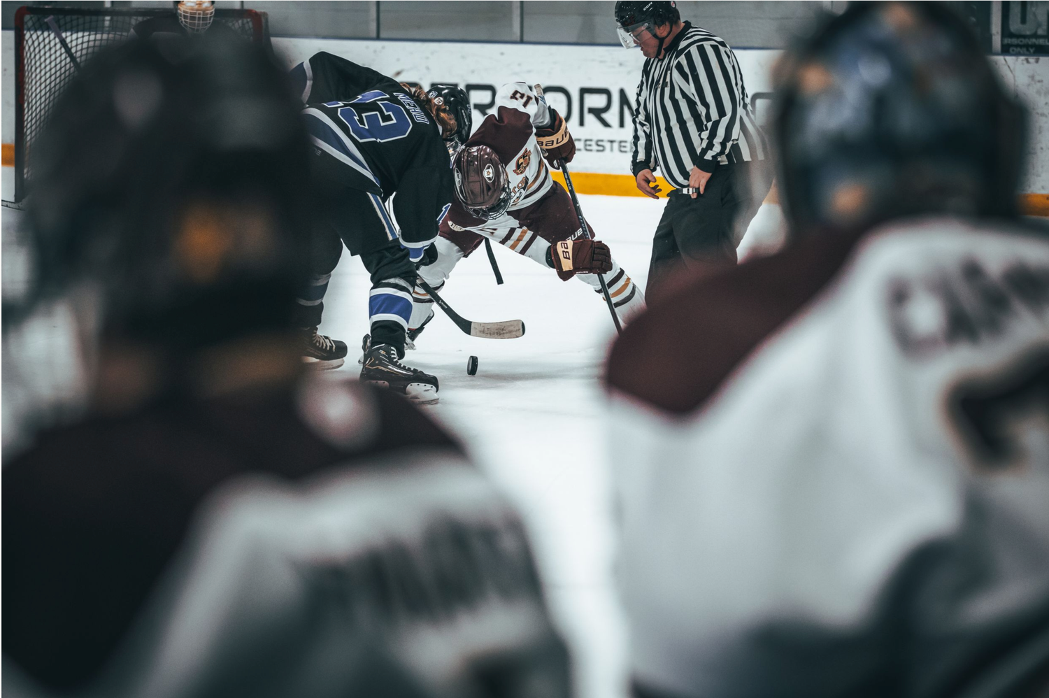 Hockey players battle for the puck during an intense game with referees watching closely on the ice.