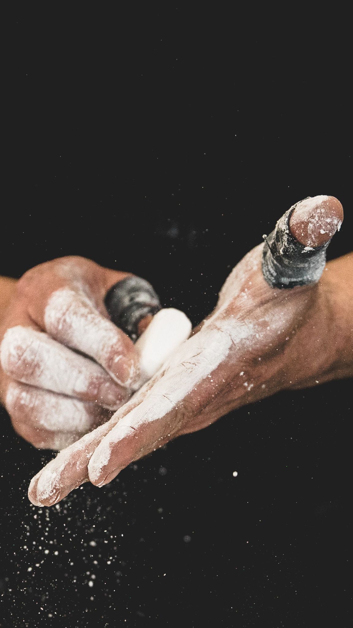 Hands clapping with white flour or powder creating a dramatic cloud effect against a black background.