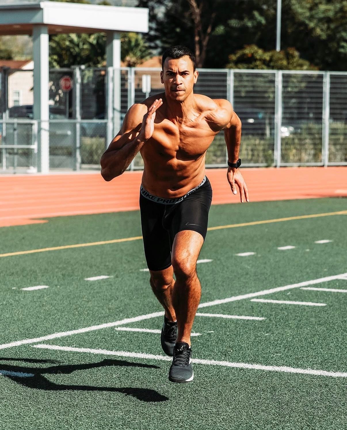 Athletic person performing explosive sprint drills on a turf field during outdoor training session.