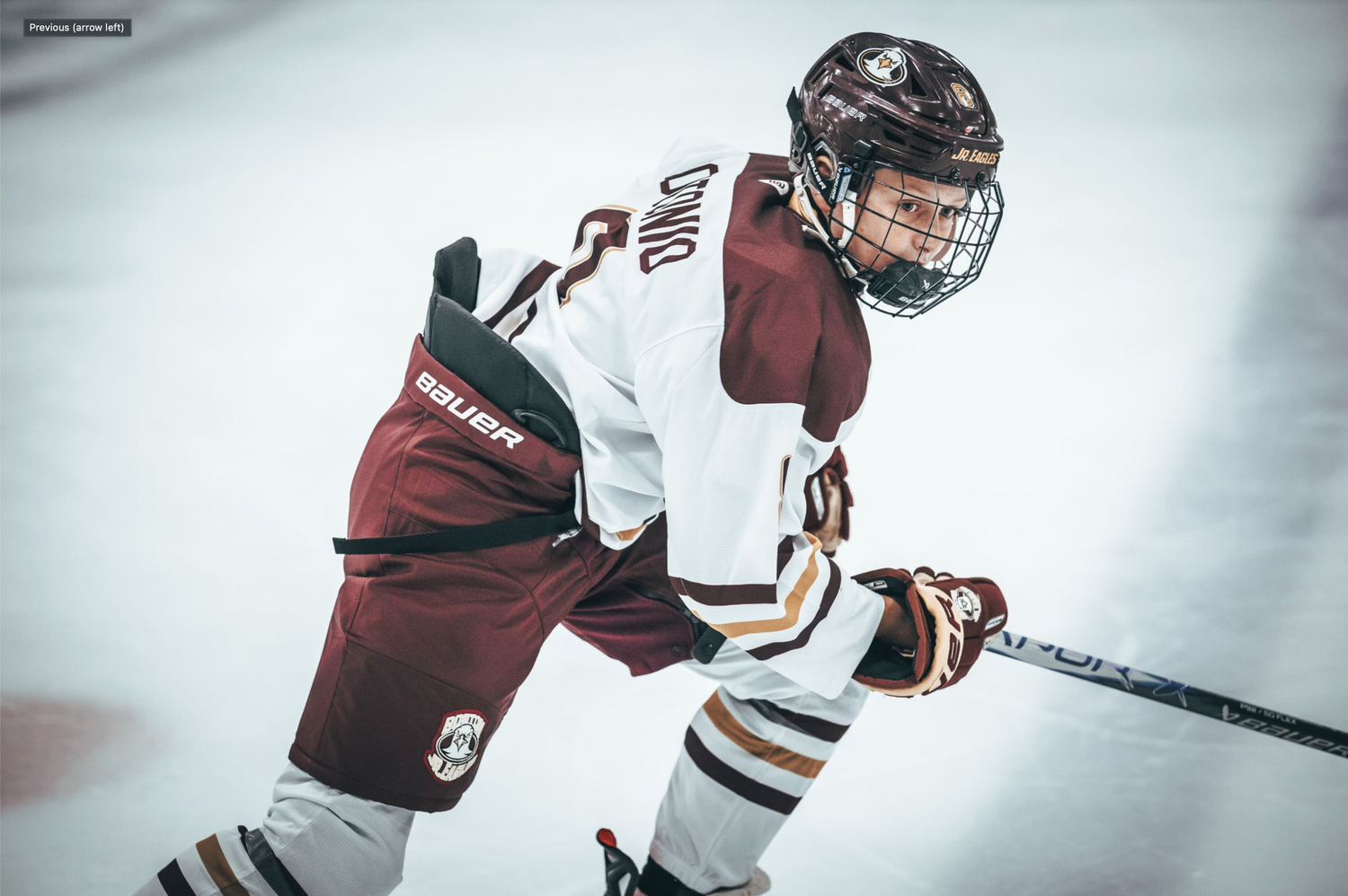 Hockey players in maroon and white jerseys battle for the puck during an intense game on the ice.