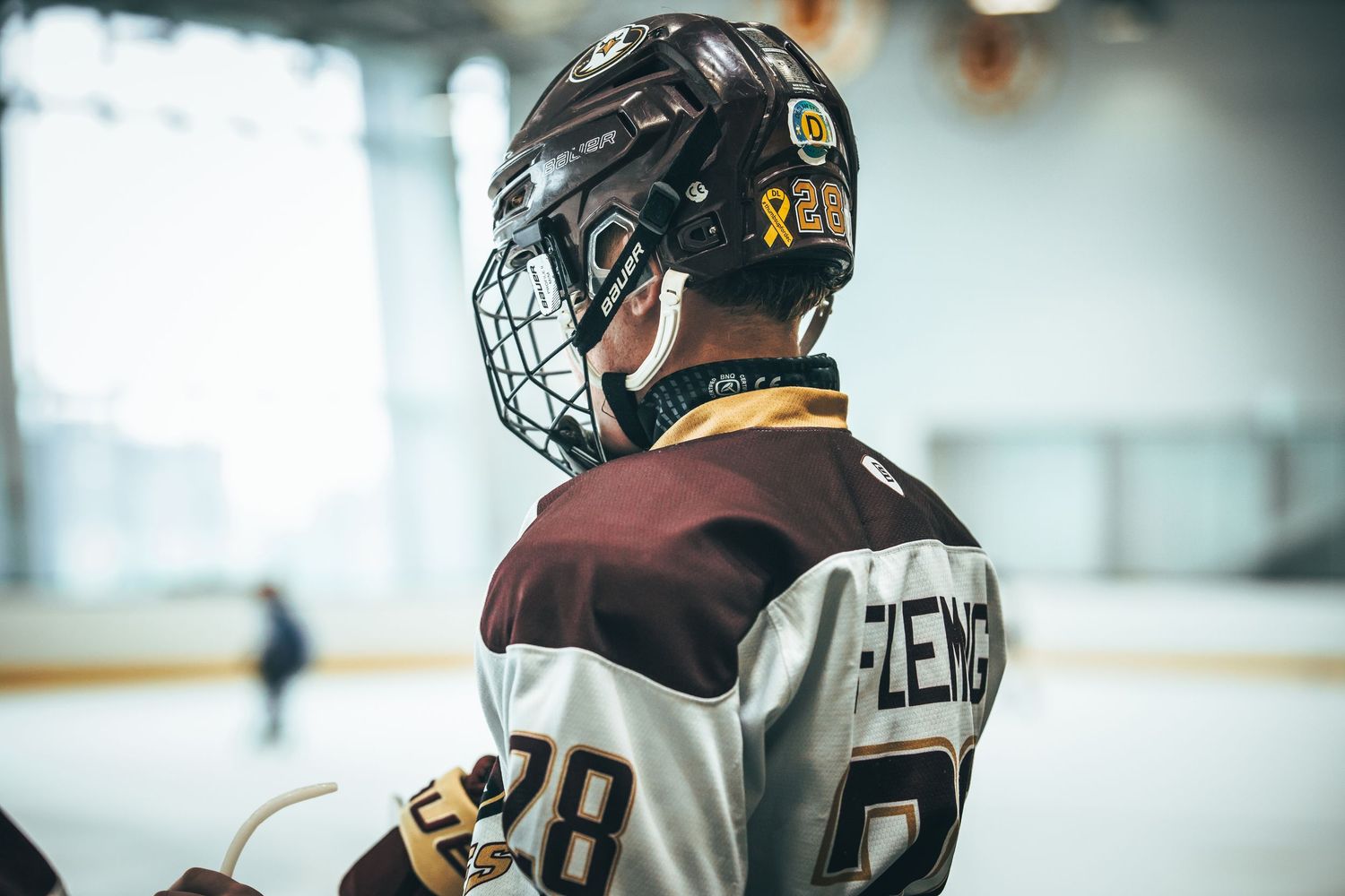 Hockey players in black and gold uniforms line up along the boards during a game on the ice rink.