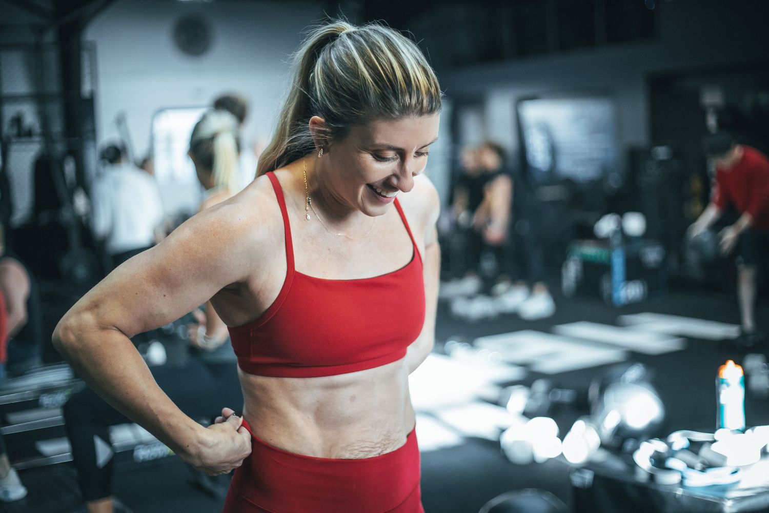 Athlete in red workout attire checking fitness progress during training session at a gym.