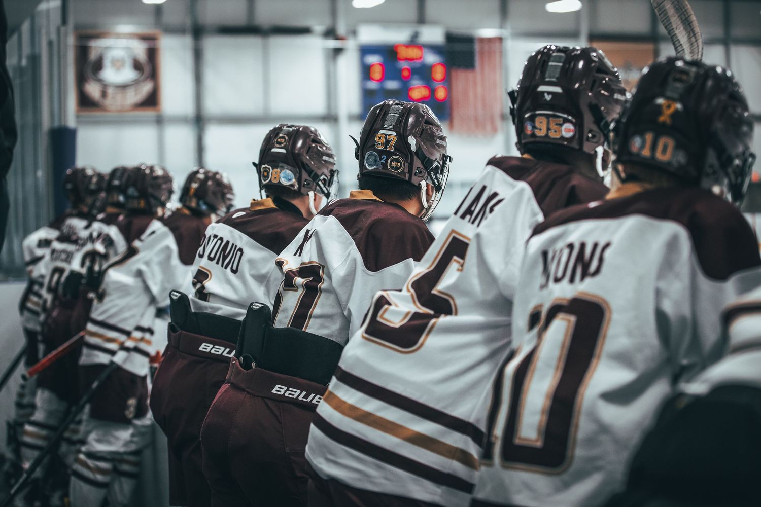 Hockey players celebrate a goal with teammates at the bench during an intense game moment.