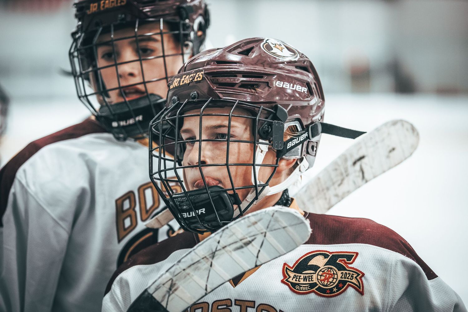 Hockey player in maroon jersey and helmet focuses intently during game action.