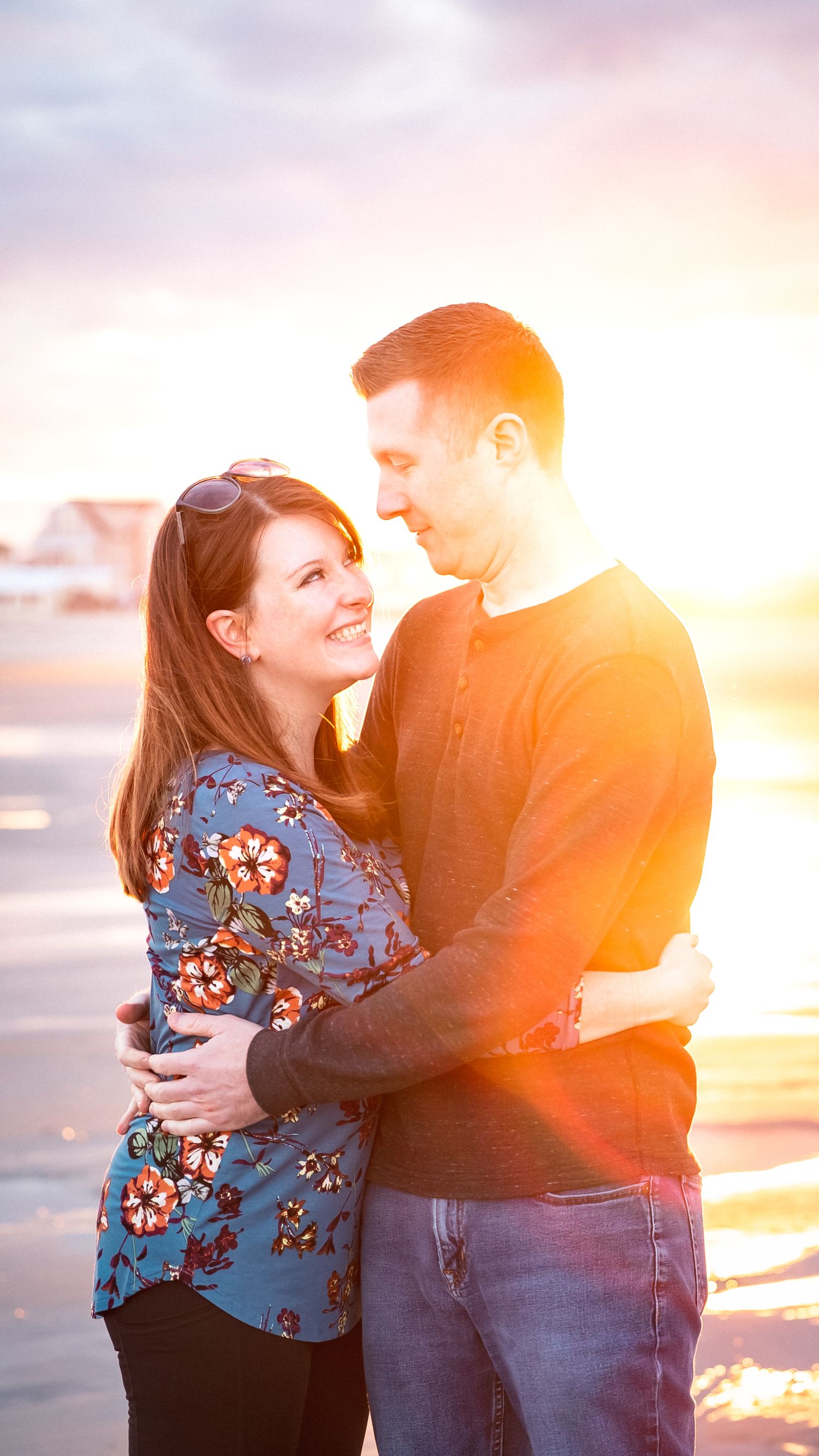 Couple embracing during golden hour sunset with warm backlight.