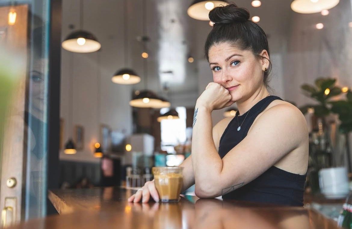 Person sitting at cafe counter with coffee cups and pendant lights creating cozy ambiance.