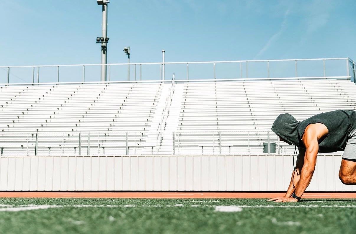 Empty high school football stadium bleachers with white metal benches and railings on a sunny day.
