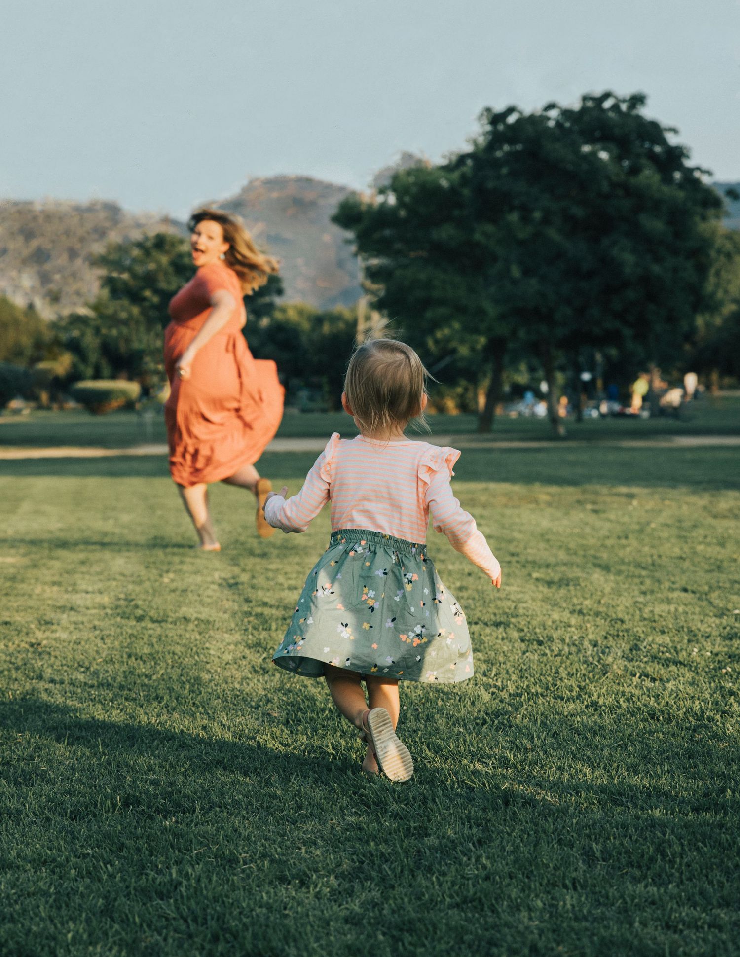 Children running and playing together in a sunny green park.