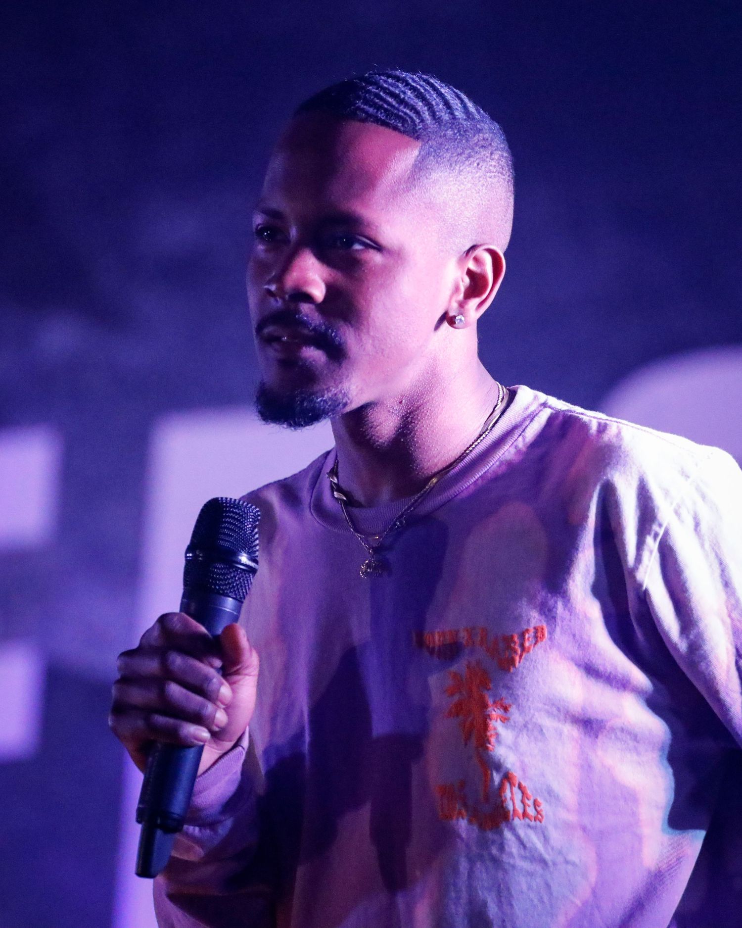 A performer in a white shirt sings into a microphone against a purple-lit background in a series of connected shots.