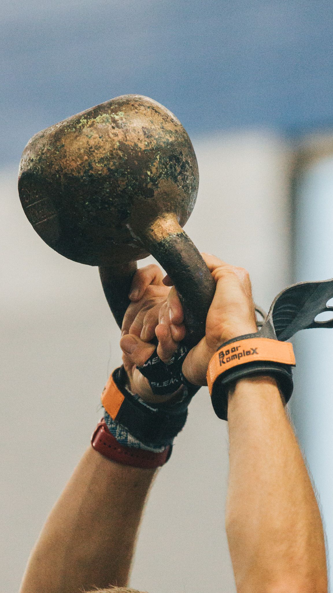 Close-up sequence showing hands lifting a heavy kettlebell overhead during a workout or training session.