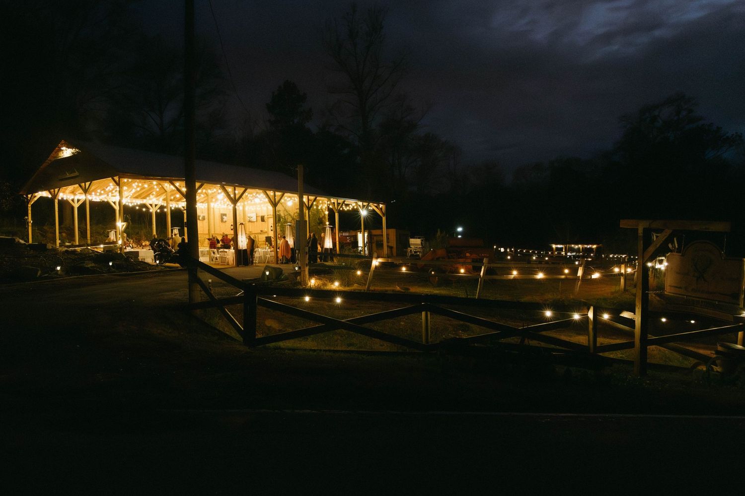 Illuminated luxury resort building glows warmly against dark night sky with landscaped grounds visible.