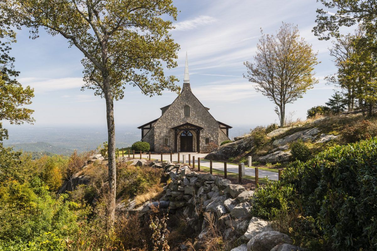 A scenic panoramic view of rolling hills and countryside with stone buildings and autumn trees dotting the landscape.