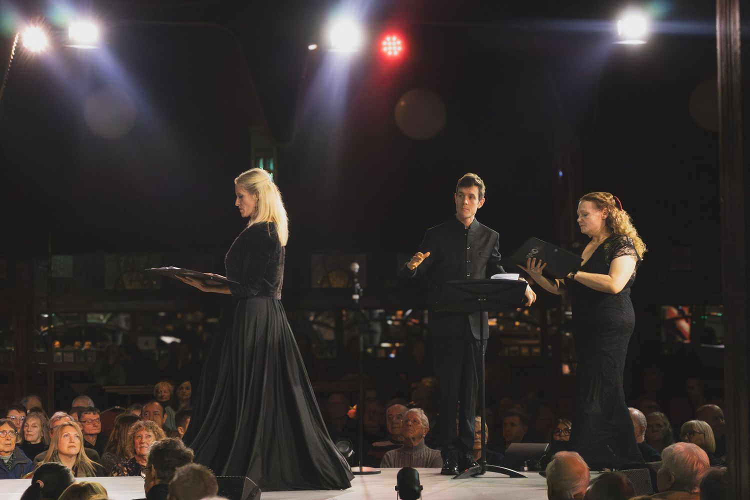 Concert stage with bright spotlights illuminating performers in formal wear.