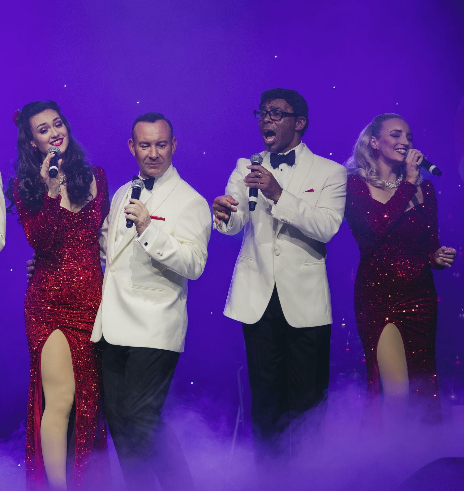 Entertainers perform a lively duet number on stage with purple lighting effects.