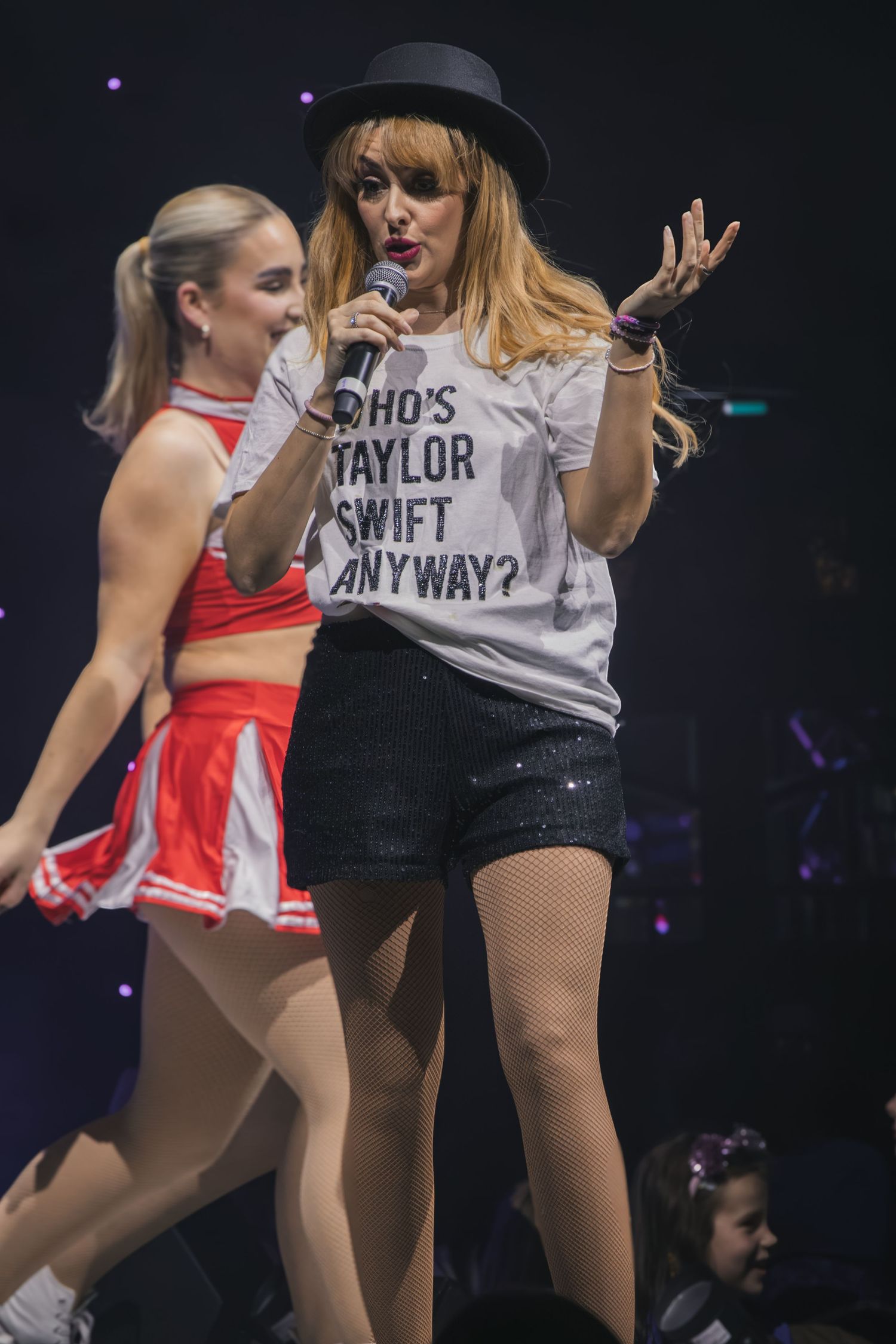Concert performance with casual attire including black hat and graphic t-shirt on stage.