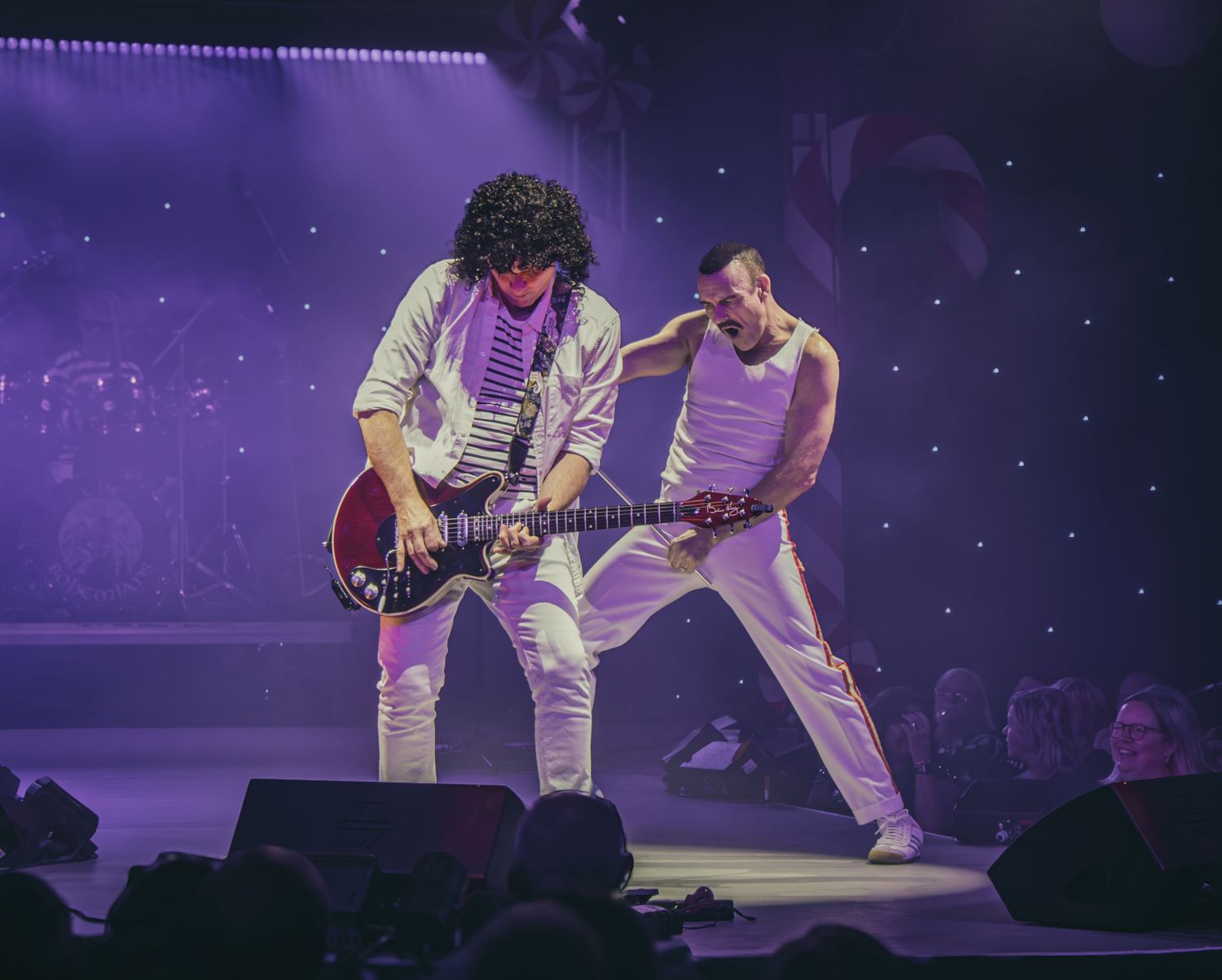 Musicians performing on stage bathed in purple lighting during a theatrical concert performance.