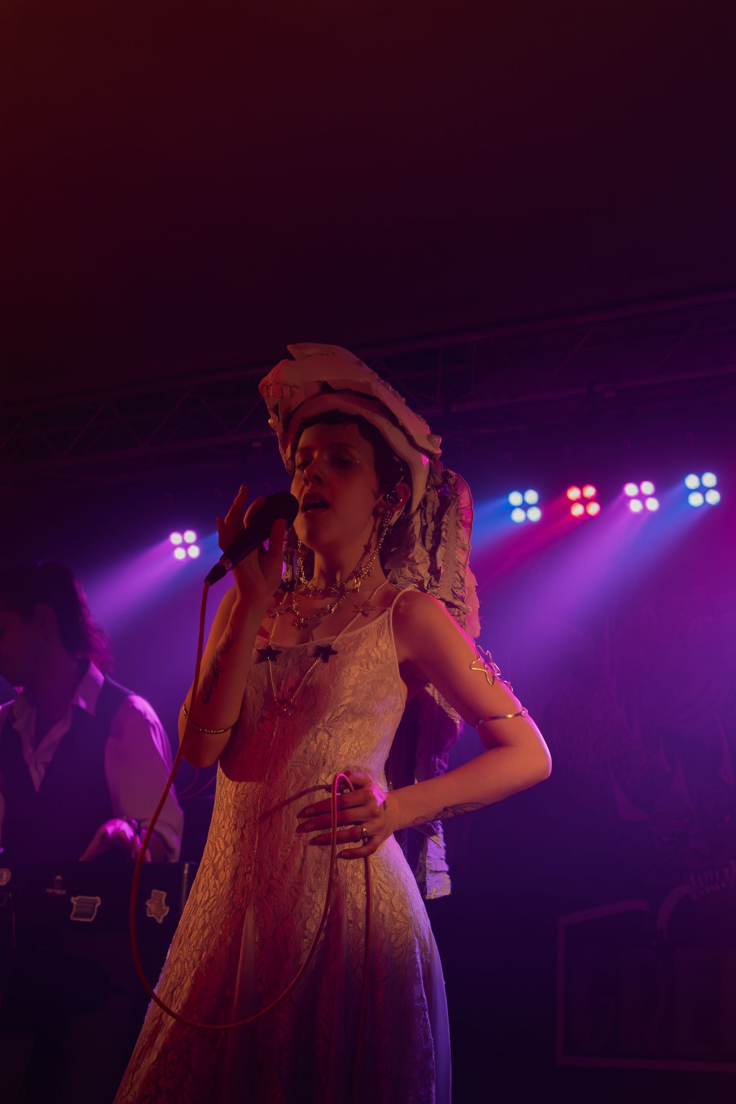 Stage performer bathed in dramatic purple lighting during an energetic concert performance.