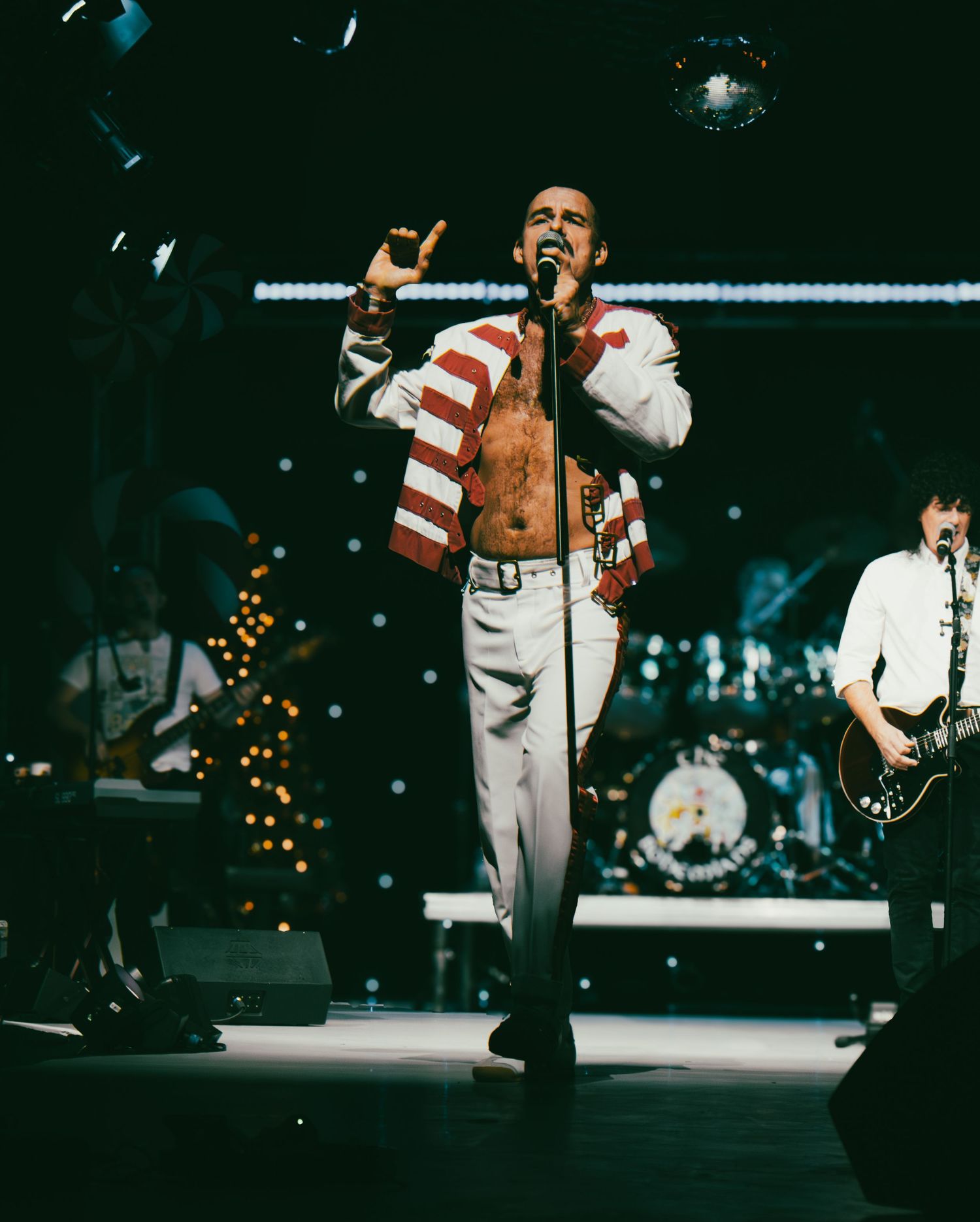 Energetic stage performance with dramatic lighting and multiple performers in white costumes.