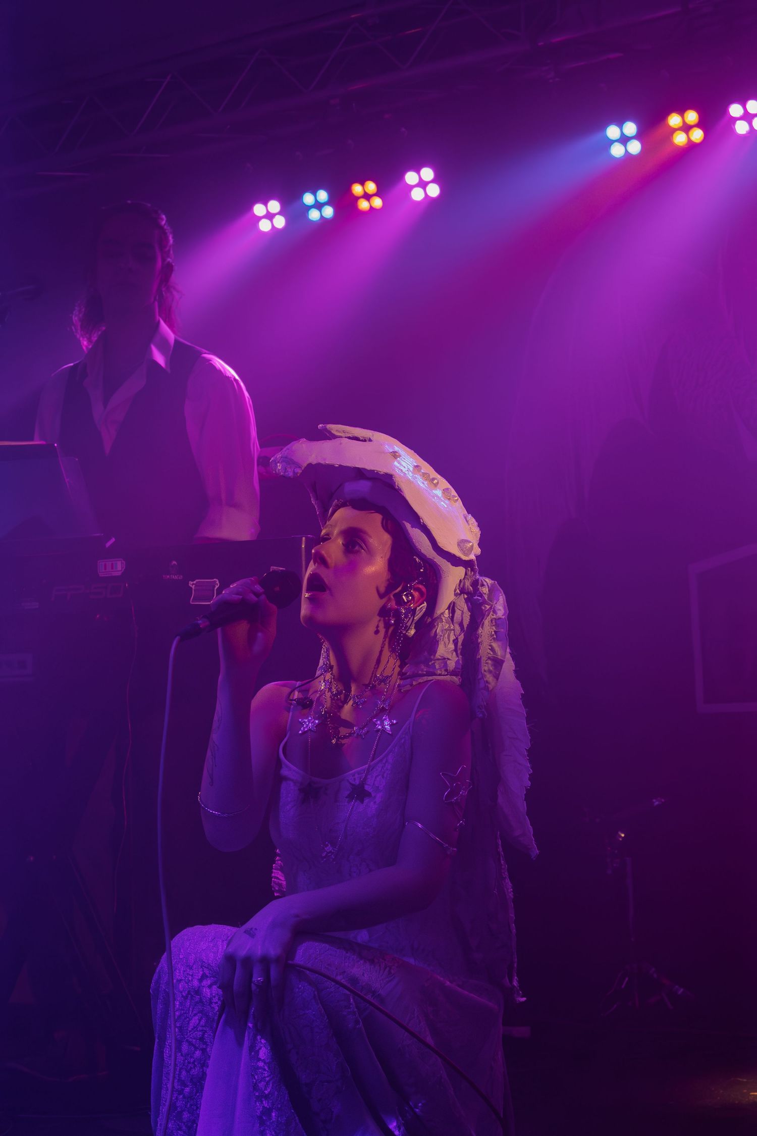 Performer on stage wearing a bandana under dramatic purple concert lighting.