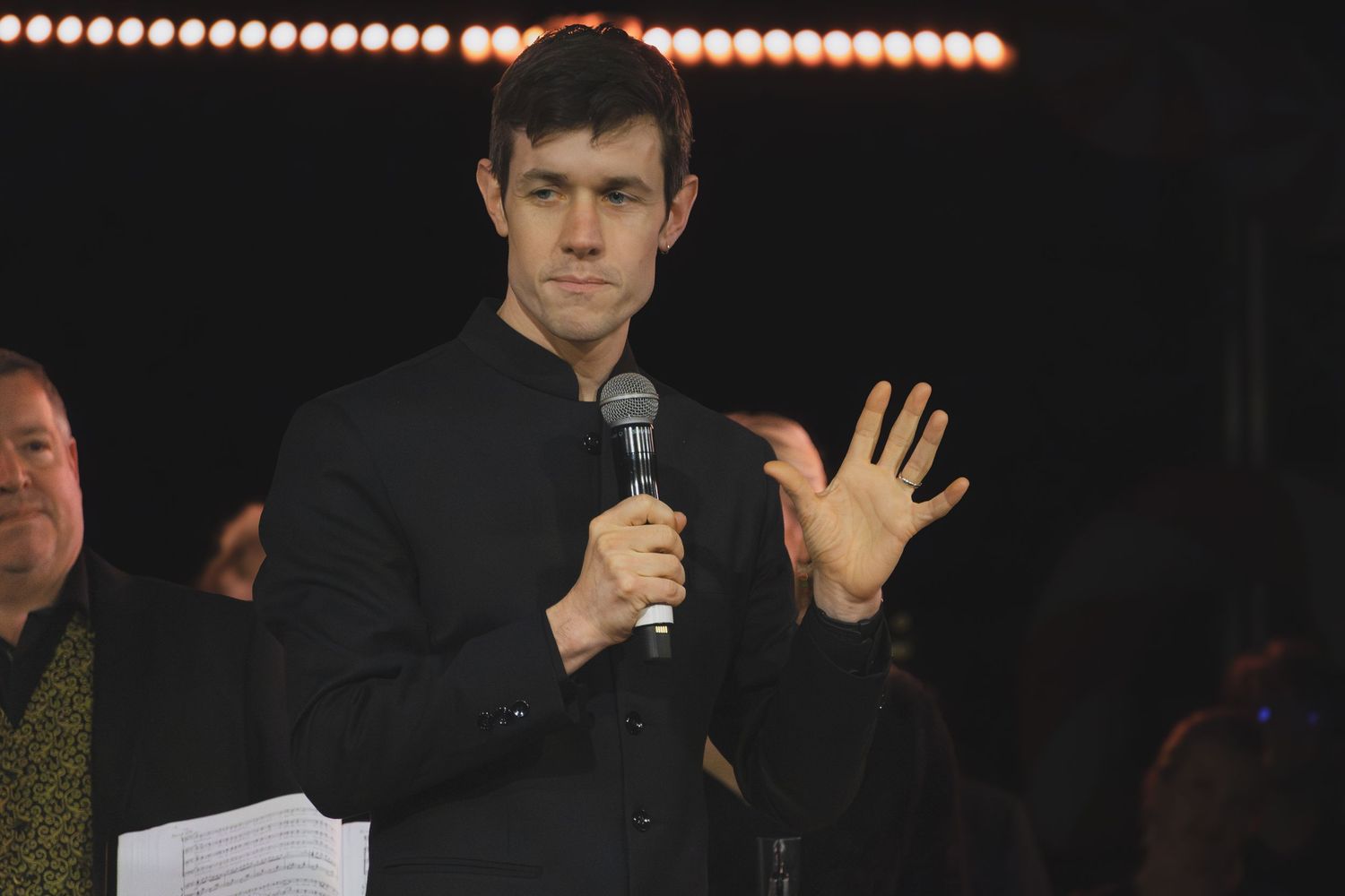 Stage performance with dramatic lighting and row of lights visible above.