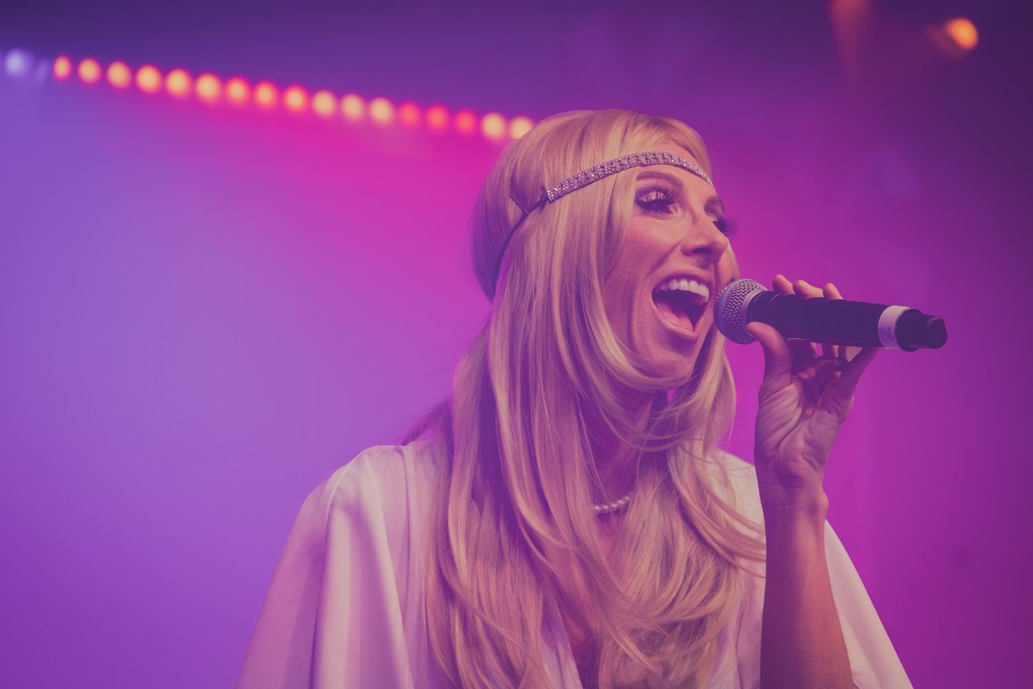 Singer performs passionately on stage with dramatic purple concert lighting effects.