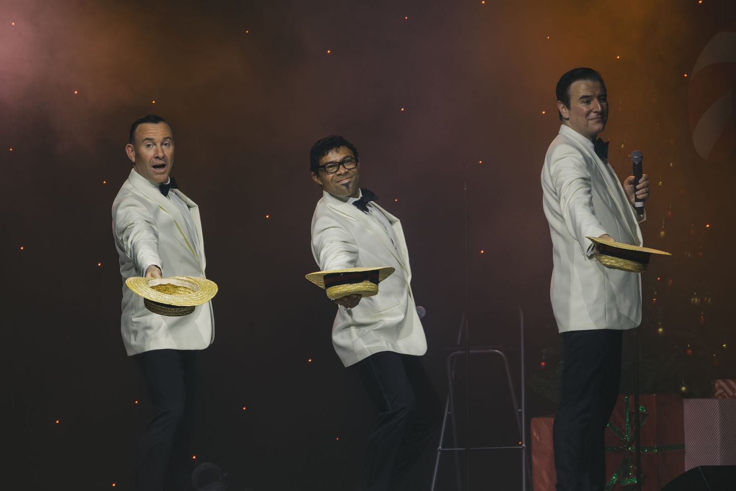 Stage performers in formal attire pose during a theatrical production.