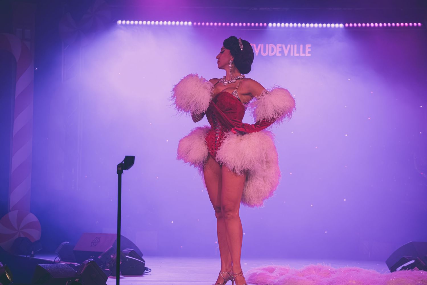 Stage performance with dramatic lighting and feathered costume elements.