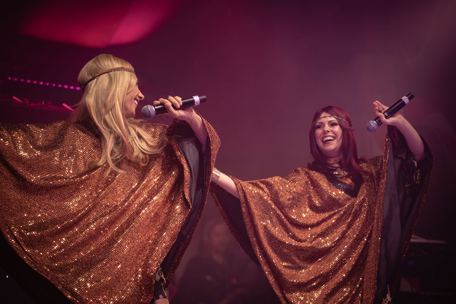 Performer in shimmering gold dress twirling dramatically on dimly lit stage.