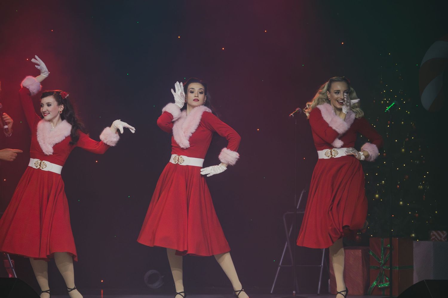 Dancers in matching red dresses perform synchronized routine on stage.