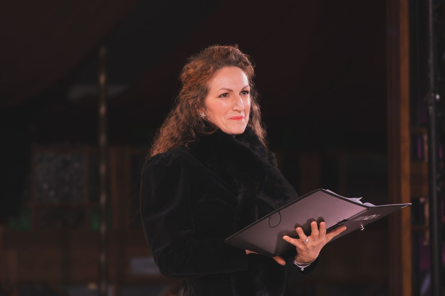 A theatrical performance unfolds on a dark stage with dramatic lighting effects.
