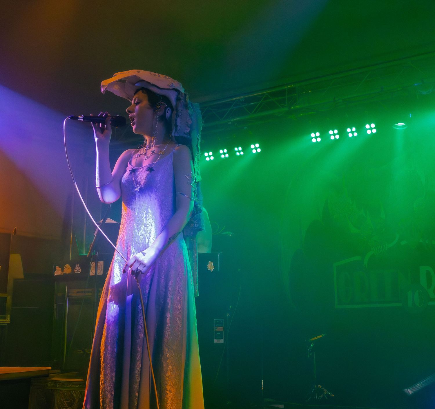 Stage performer silhouetted against vibrant green concert lighting during a live show.