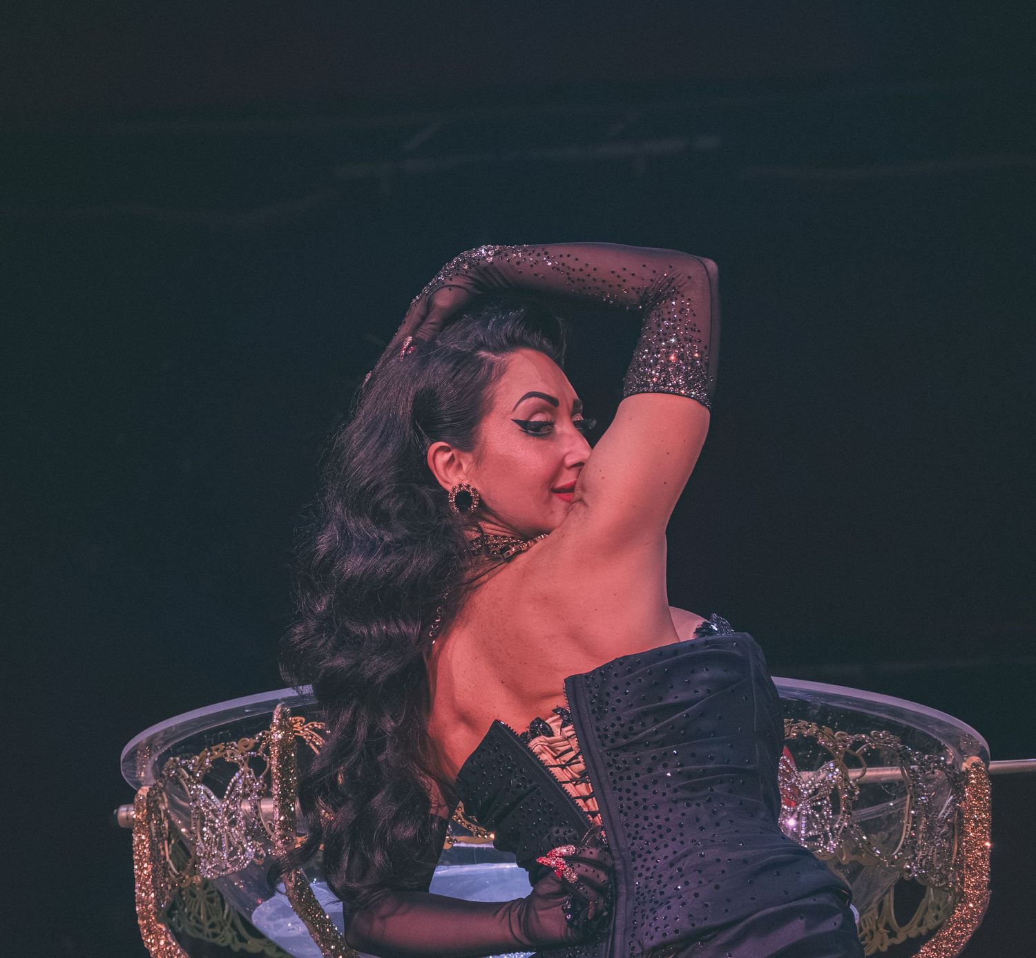 A performer in a corset strikes a dramatic pose during a cabaret show.
