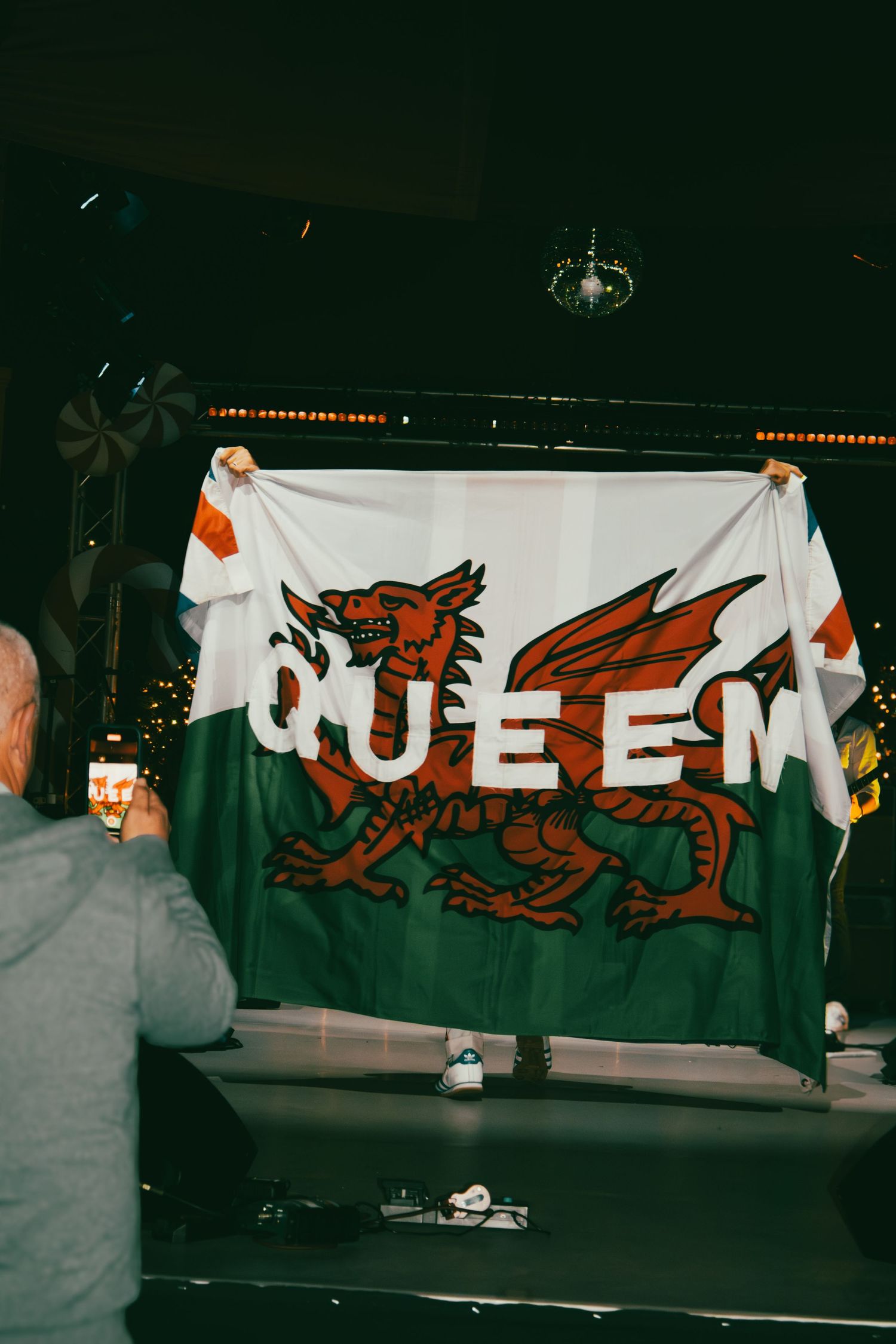 A series of connected photos showing supporters holding up a large white banner with a red Welsh dragon design.
