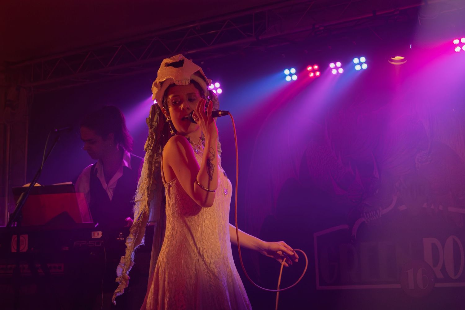 Artist performing on stage with dynamic purple and blue lighting effects creating a moody atmosphere.