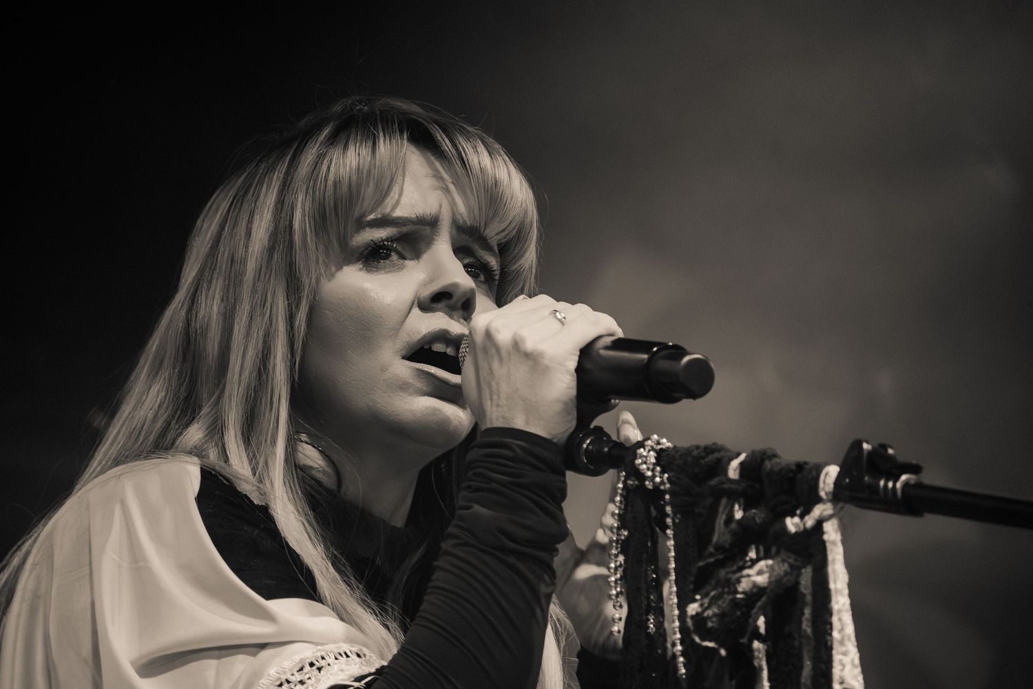 A monochrome concert photo captures an emotional vocal performance on stage.